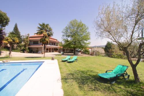 a yard with a swimming pool and two green chairs at Casa do Lago in Amares