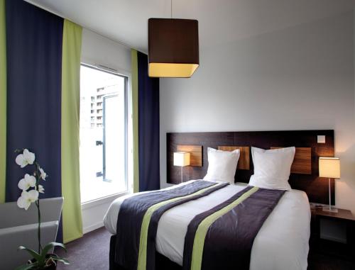 um quarto com uma cama grande e uma janela grande em Lagrange Apart’Hotel Paris-Boulogne em Boulogne-Billancourt