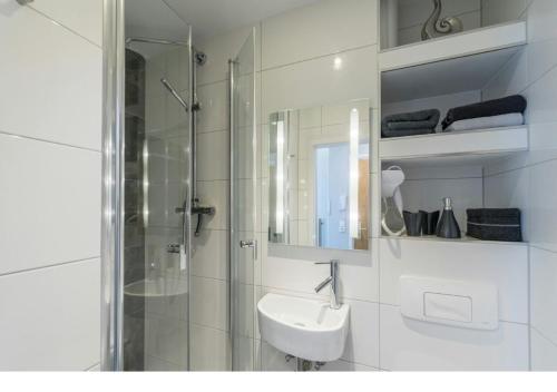 a white bathroom with a shower and a sink at Gepflegte und moderne Ferienwohnung in der Neuseenlandschaft in Neukieritzsch