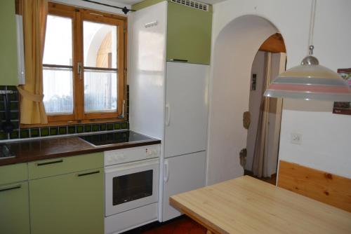 kuchnia z zielonymi i białymi urządzeniami oraz stołem w obiekcie Apartment Bos-cha w mieście La Punt-Chamues-ch