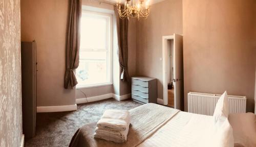 a bedroom with a bed and a window and a chandelier at 7 Llewelyn Avenue in Llandudno
