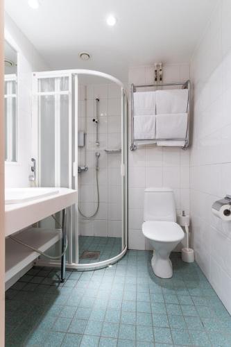 a bathroom with a shower and a toilet and a sink at Hotel Fjalar in Salo