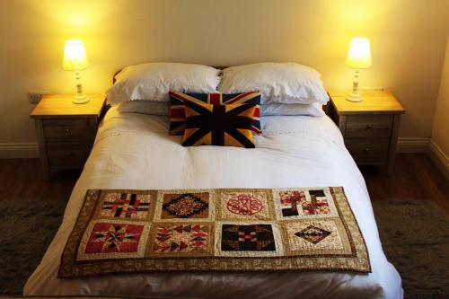 a bed with two lamps and a quilt on it at Two Moors Retreat in Witheridge