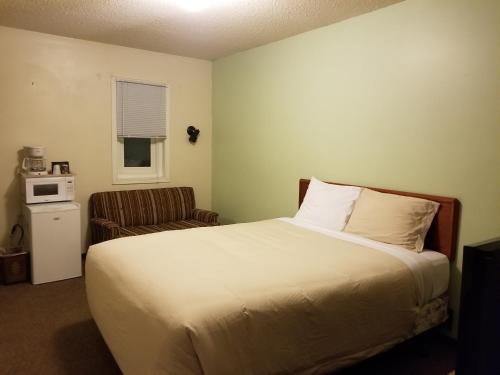 a small bedroom with a bed and a chair at Melsask Motel in Melville