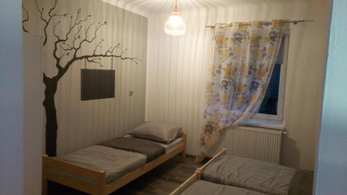 Cette chambre comprend deux lits et un arbre sur le mur. dans l'établissement Folwark Anna, à Kamienica Polska