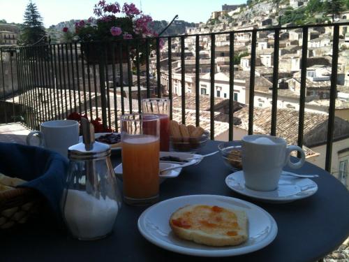 a table with a plate of food and coffee on a balcony at I Tetti di Siciliando in Modica