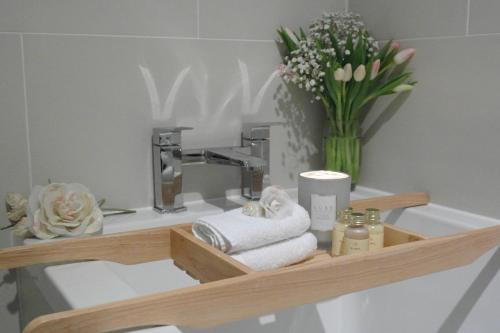 a shelf with towels and a sink with a vase of flowers at Ashford house 'The Snug' private hot tub in Fylingthorpe