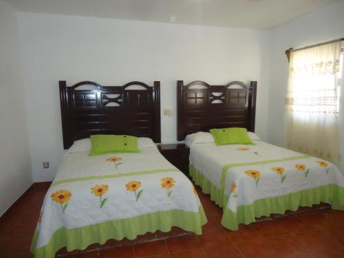 a bedroom with two beds with green and yellow pillows at Hotel San Isidro in Bernal