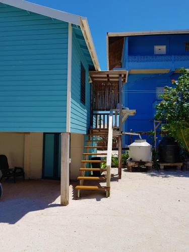 a blue house with a wooden staircase in front of it at Carolyn's House in Caye Caulker