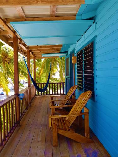 a porch with a hammock and a blue house at Carolyn's House in Caye Caulker
