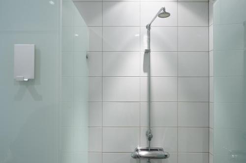 a shower in a white tiled bathroom at Archipelago Hostel Old Town in Stockholm