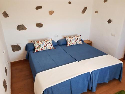 a bedroom with a blue and white bed with two pillows at Casa el Gallo in Teguise