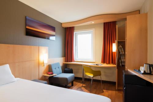 een hotelkamer met een bed en een bureau bij ibis Rotterdam Vlaardingen in Vlaardingen