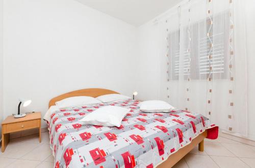 a bedroom with a bed with a red and white comforter at Apartments Mime in Pirovac