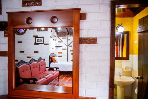 a mirror in a room with a couch and a bedroom at Jardines De Chamana in Baños