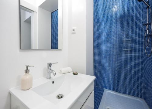 uma casa de banho com um lavatório e um chuveiro com azulejos azuis em Casa dos Apóstolos em Évora