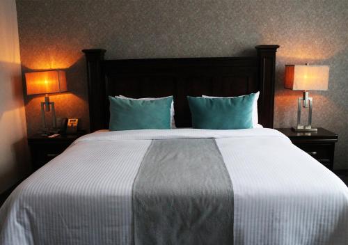 a bedroom with a large bed with blue pillows and two lamps at Gran Hotel Concordia San Luis Potosi in San Luis Potosí