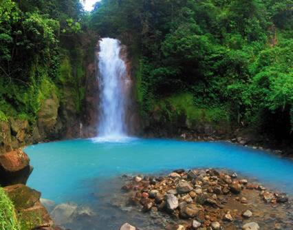 a waterfall in the jungle with a pool of blue water at Coco Beach Home in Coco