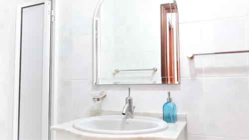 Un baño blanco con lavabo y espejo. en Casa da Avó Irene, en Funchal