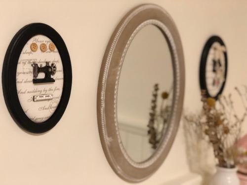 a mirror hanging on a wall with two clocks at Yo Muma Homestay in T'ien-wei