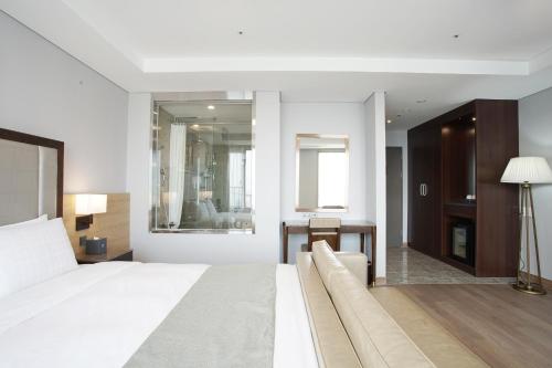 a bedroom with a large white bed and a desk at Stanford Hotel Busan in Busan