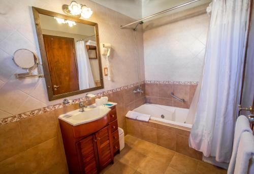 a bathroom with a sink and a tub and a mirror at Hosteria Sirenuse in Mar del Plata