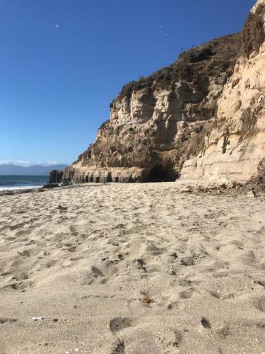 a beach with footprints in the sand next to a cliff at Hostal Quiriyuca Sur in Horcón
