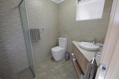 La salle de bains est pourvue de toilettes, d'un lavabo et d'une douche. dans l'établissement Lakeview Apartments, à Kununurra