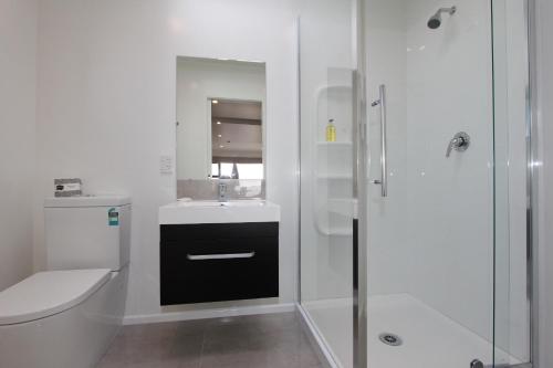 a bathroom with a toilet and a sink and a shower at Blue Marlin Apartments in Whitianga