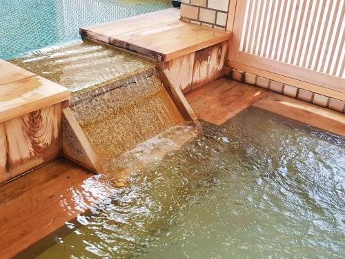 a pool of water with a wooden platform in the water at Atami Onsen Hotel Yume Iroha in Atami