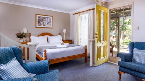 a hotel room with a bed and two chairs at Honeysuckle Cottages in Stanthorpe