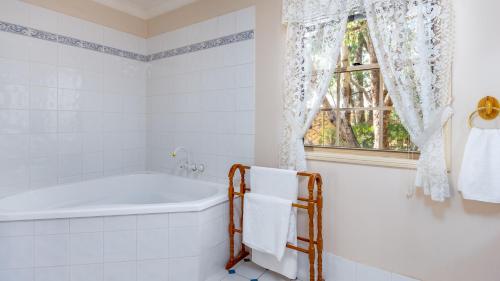 a bathroom with a tub and a window at Honeysuckle Cottages in Stanthorpe