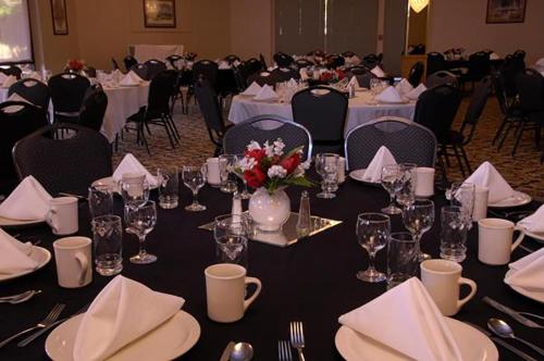 a room filled with tables with white tablecloths and chairs at Yuma Inn & Suites in Yuma