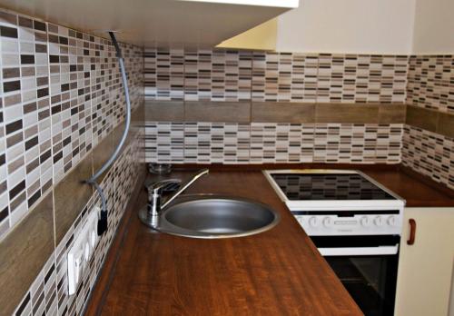 Il comprend une petite cuisine équipée d'un évier et d'une cuisinière. dans l'établissement Weninger Studio Apartman, à Kiskunhalas
