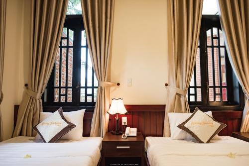 two beds in a room with two windows at Spring Garden Villa in Hue