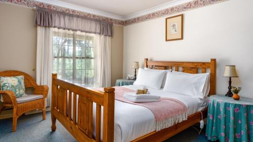 a bedroom with a bed and a chair and a window at Honeysuckle Cottages in Stanthorpe
