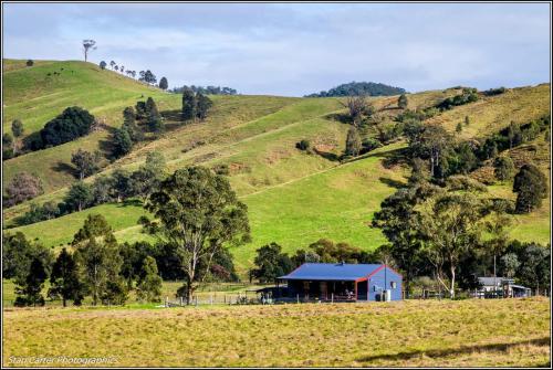 a blue barn in a field on a hill at The Wattle Lodge in Glendon Brook