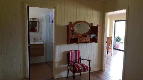 a bathroom with a chair and a sink and a mirror at The Wattle Lodge in Glendon Brook