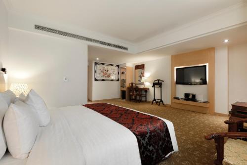 a hotel room with a white bed and a flat screen tv at Hotel Sunshine in Kaohsiung
