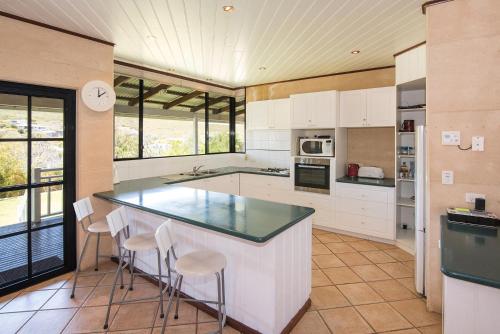a kitchen with white cabinets and a counter with stools at The Southouse Beachouse in Gnarabup
