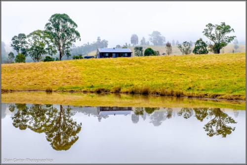 a house on a hill next to a body of water at The Wattle Lodge in Glendon Brook