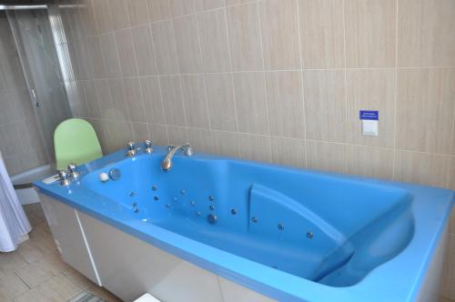 a blue bath tub in a bathroom with a green chair at FWP Rybniczanka - Wanda in Lądek-Zdrój