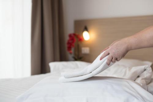a person is holding a napkin on a bed at Residence iL Lago in Cluj-Napoca