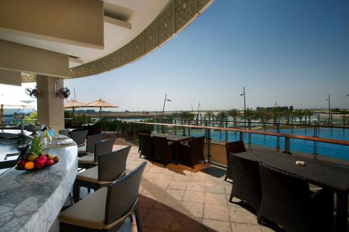 a restaurant with a pool and tables and chairs at Bab Al Qasr Residence in Abu Dhabi