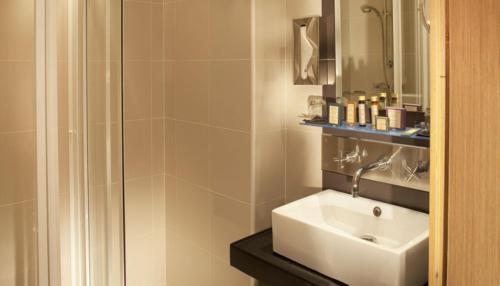 een badkamer met een witte wastafel en een douche bij Villathena in Parijs