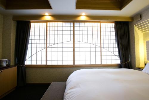 a bed in a room with a large window at Kyoto Kamanza Hotel in Kyoto