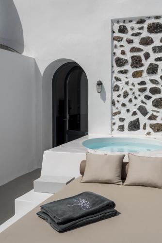 a pool in a room with a towel on a couch at Honeymoon Petra Villas in Imerovigli