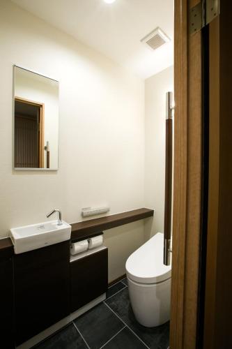 a bathroom with a toilet and a sink and a mirror at Kyoto Kamanza Hotel in Kyoto