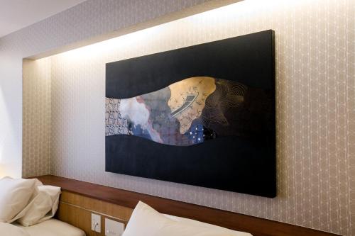 a painting hanging on a wall above a bed at Kyoto Kamanza Hotel in Kyoto