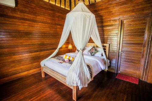 Maha Guru Huts في نوسا ليمبونغان: غرفة نوم بسرير مع ناموسية